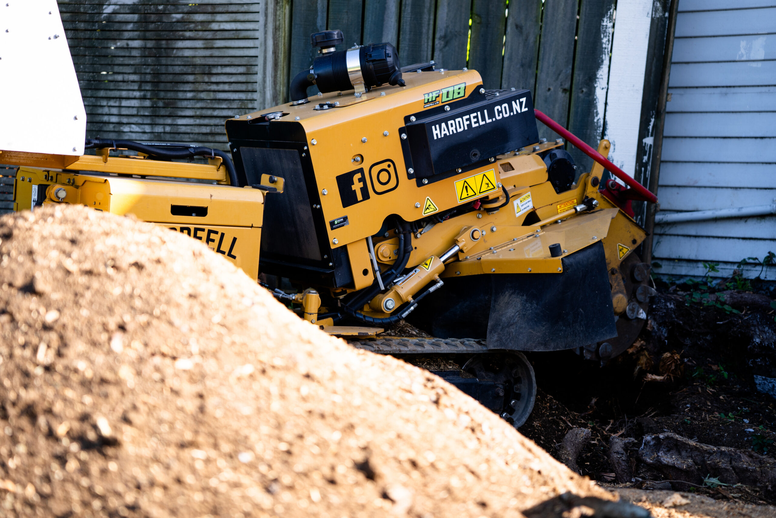 Hardfell branded Rayco tracked stump grinder working beside a large stump in Auckland