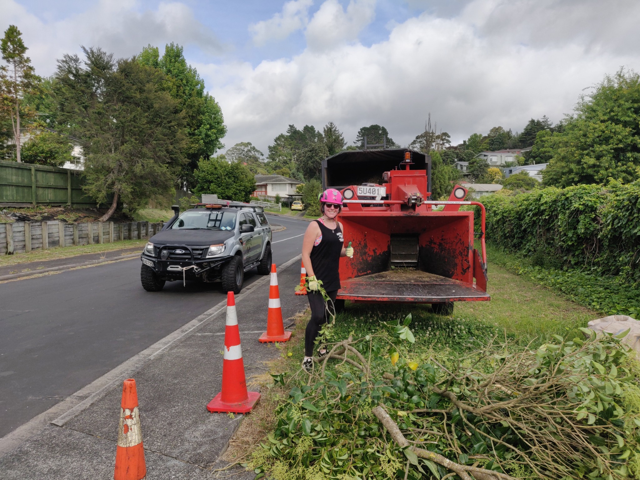 Lucy Hardman beside the chipper on a Hardfell worksite, with the truck and traffic cones visible
